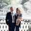 A man, woman, and toddler posing in front of a large, white splashing park fountain.