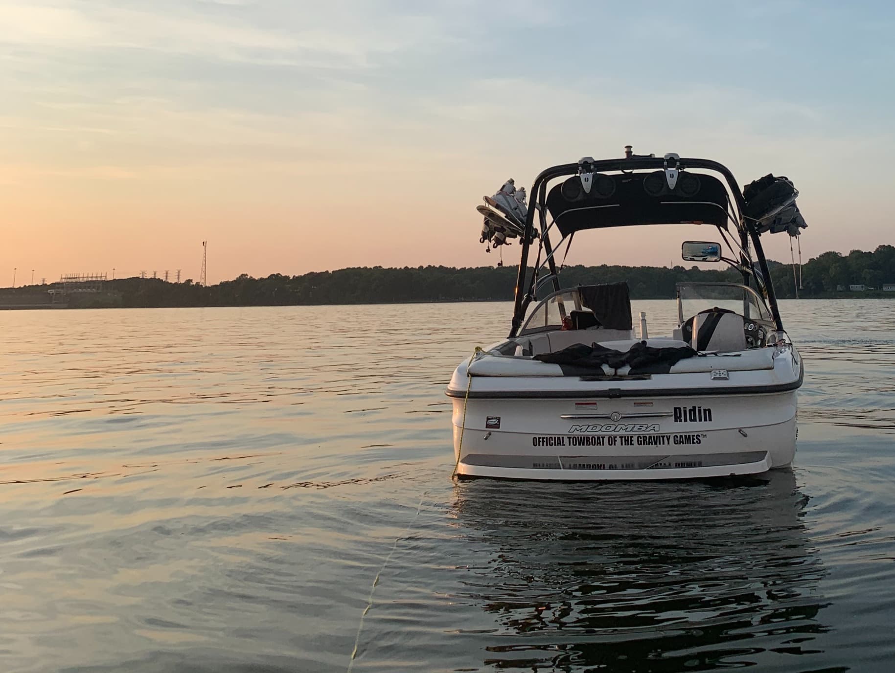 Rear view of a white Moomba boat on a calm lake during a golden sunset.